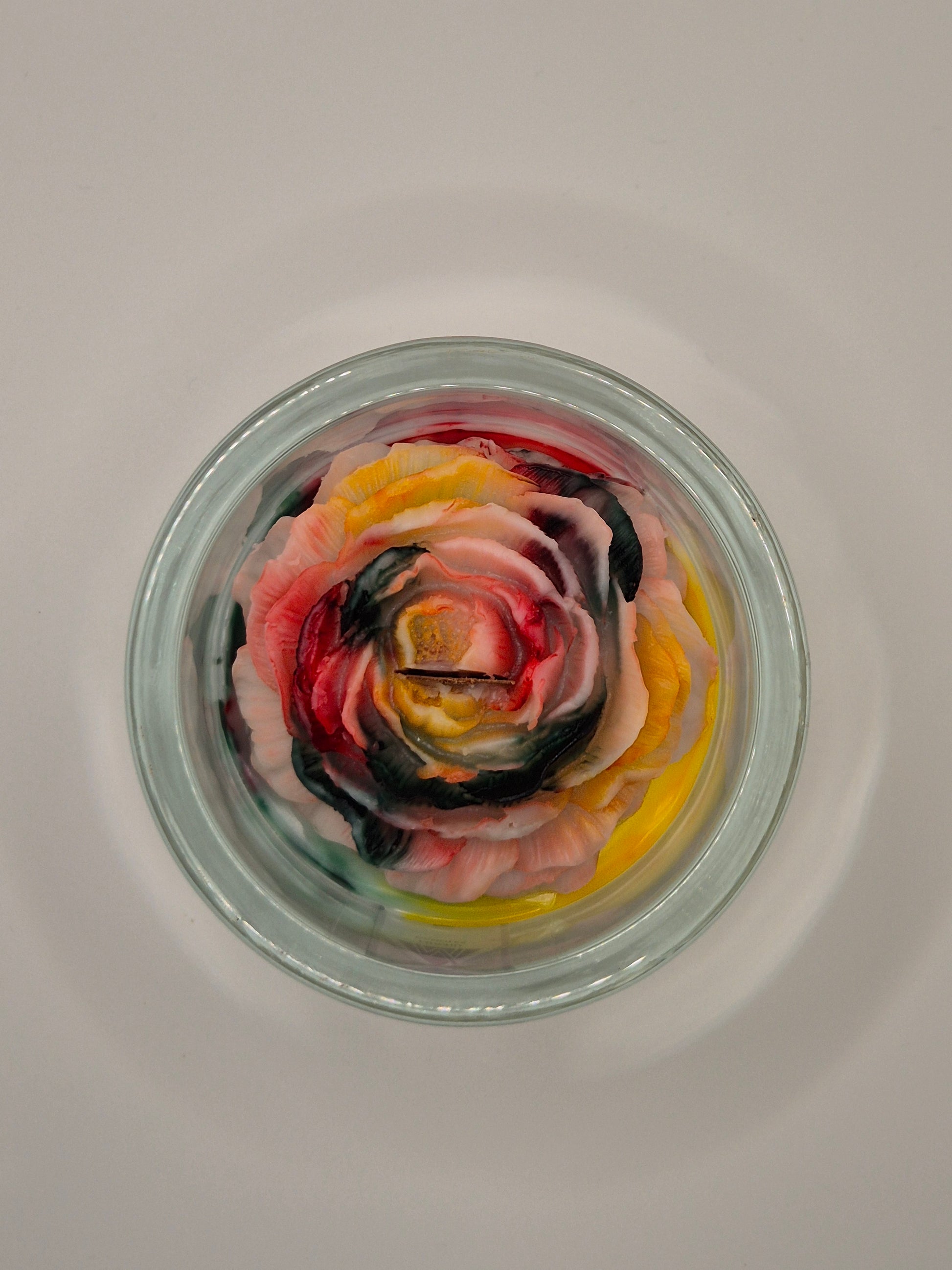 Colourful rose-shaped candle in a glass jar called Nutcracker on a white background